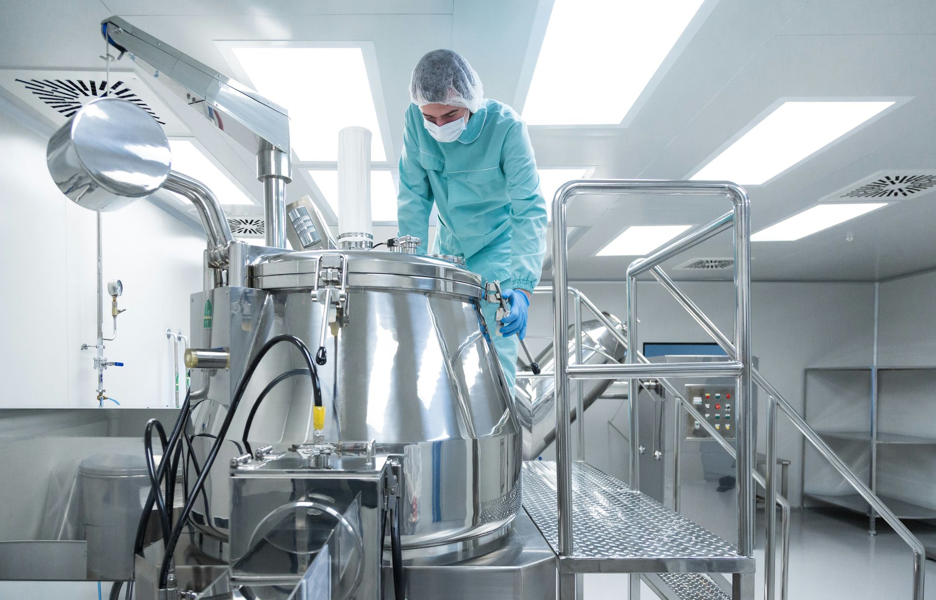 Operator working with a stainless steel blender in a cleanroom